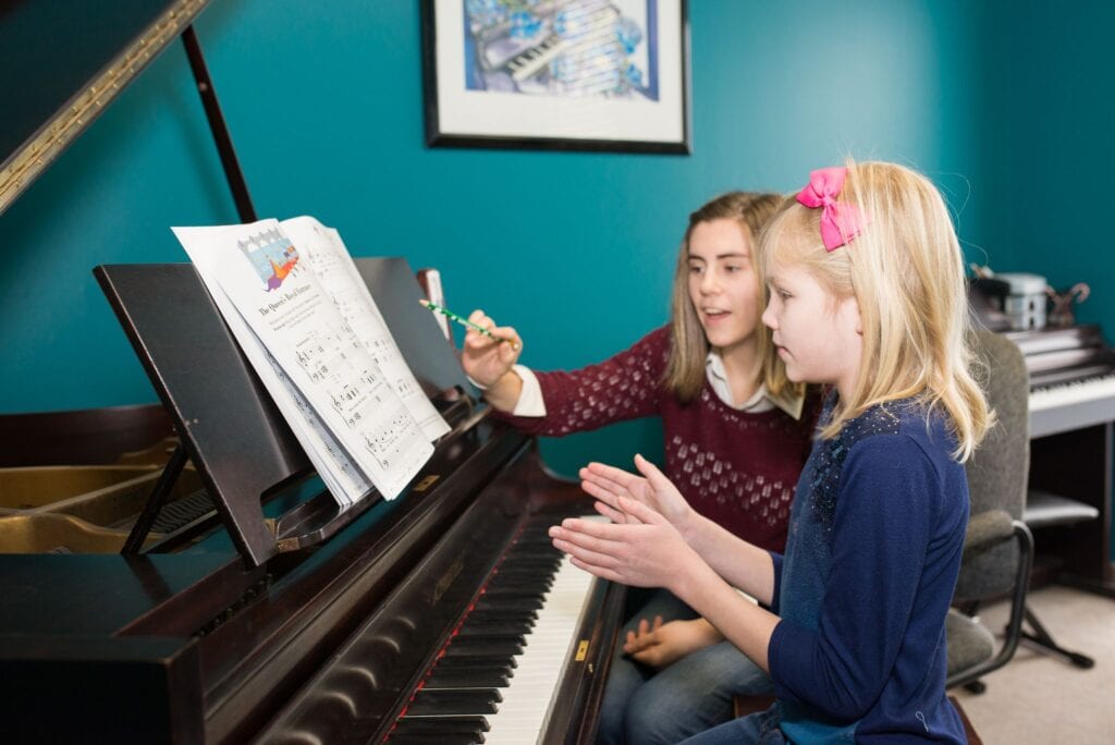 A young piano student at the piano with her teacher at the Academy of Music in Milton