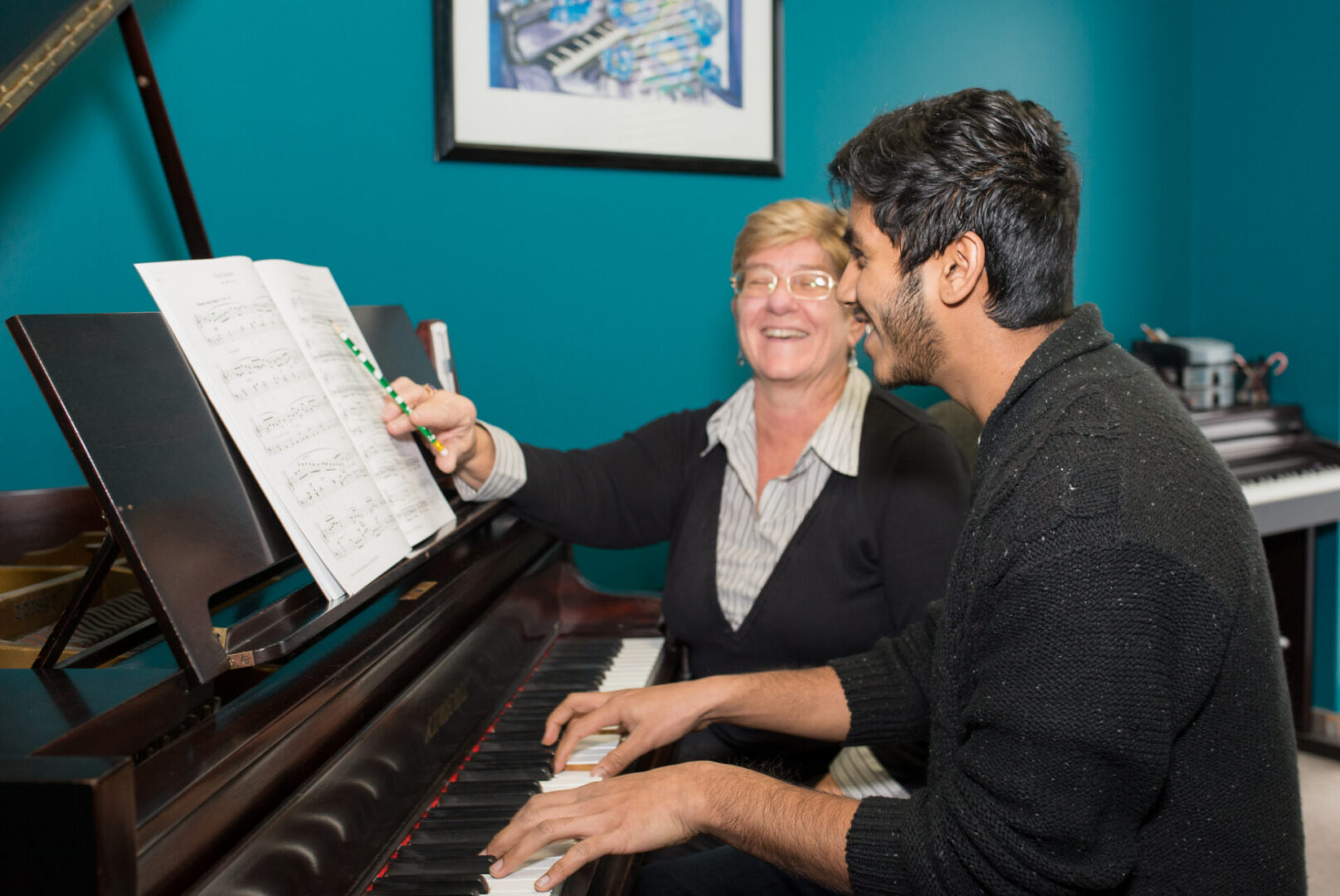 An adult student at the piano with his teacher at the Academy of Music in Milton