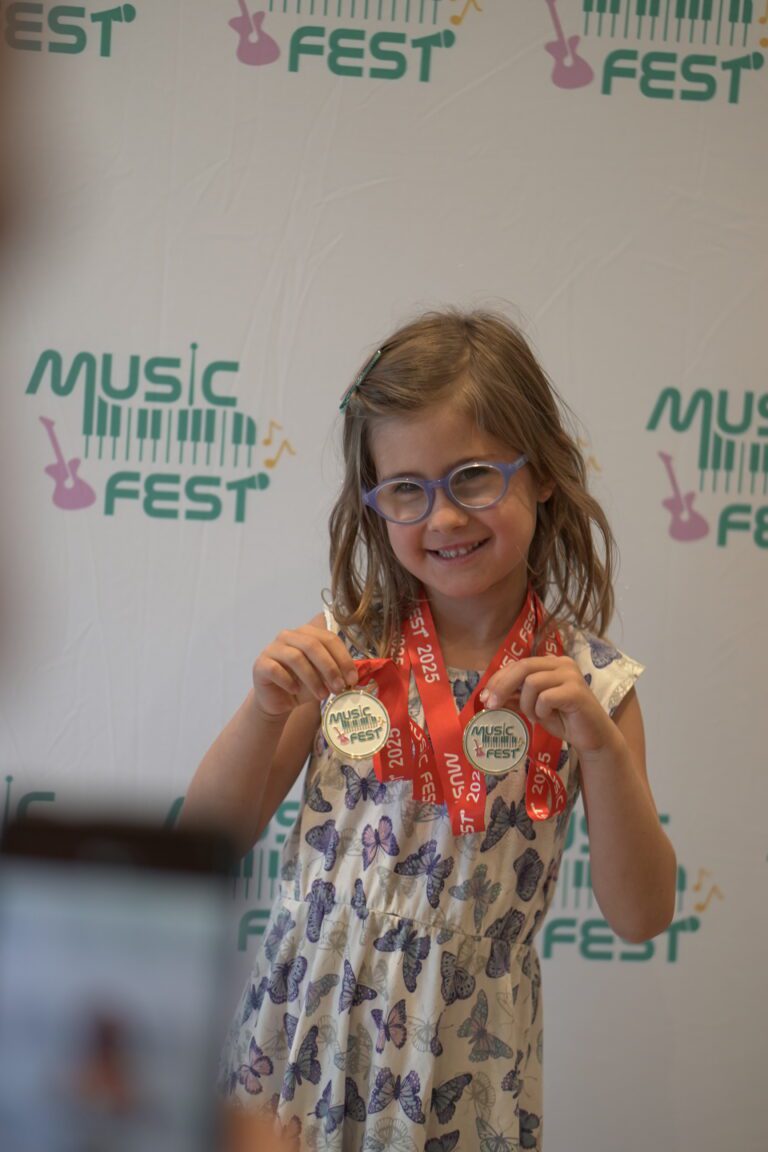 A young Academy of Music student holding her Music Fest medals