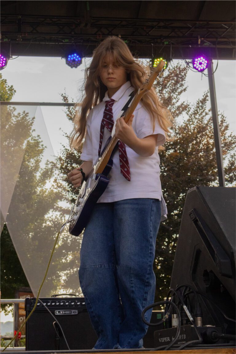 An Academy of Music guitar student performing on stage in Milton